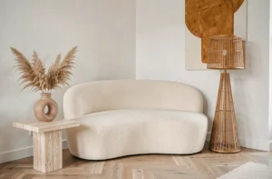 Coin salon moderne décoré avec un canapé bouclé crème, une table en travertin et un vase en céramique avec herbes de la pampa, style tendance Cherry Déco
